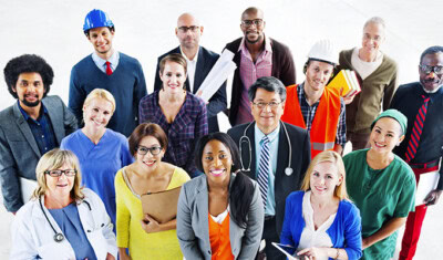 A diverse group of professionals including doctors, construction workers, engineers, and office workers stand together and smile at the camera, showcasing the success of our comprehensive Career Education initiative.