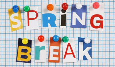 Text "Spring Break" spelled out using cut-out letters pinned to a grid-pattern background with colorful push pins, perfect for sharing travel tips.