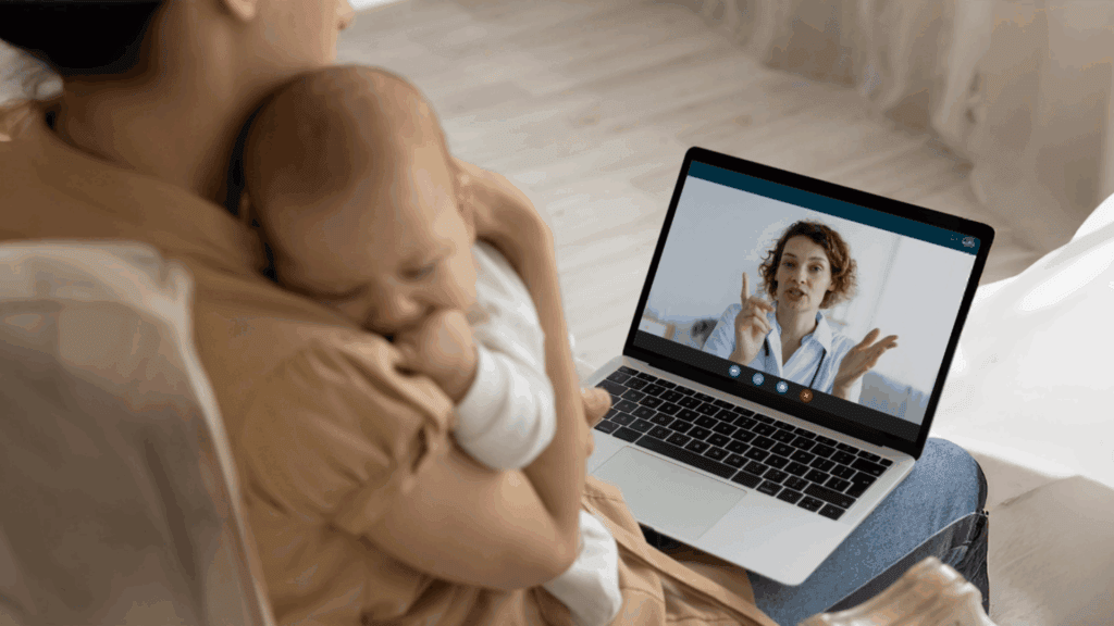 An adult holding a sleeping baby on their lap has a video call with an Alliance Health professional on a laptop, taking steps to stay healthy from the comfort of home.
